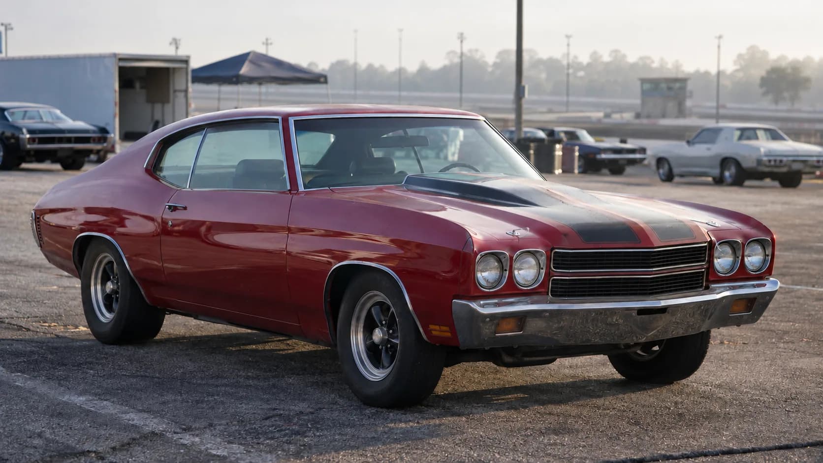 A red 1970 Chevelle SS 454 with black stripes and a cowl-induction hood in a drag strip pit area