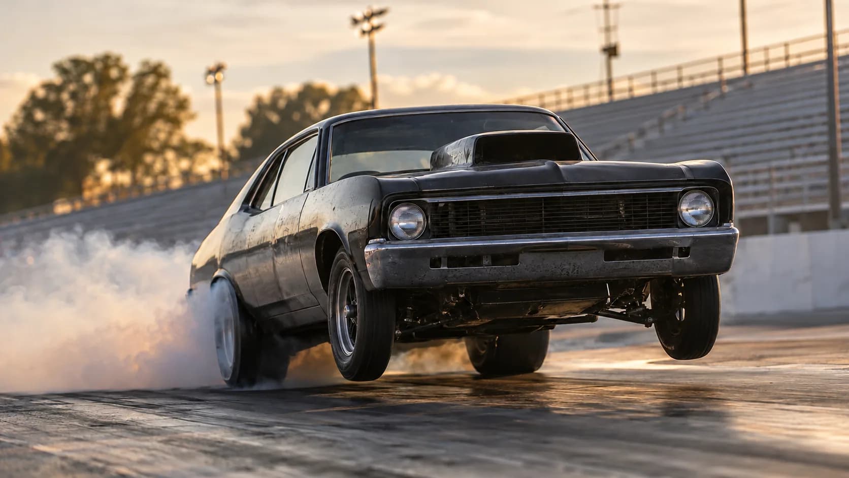 Front wheels off the ground, smoke rolling off the tires, grandstands glowing at sunset. Drag strips are where big-inch muscle earned its name.