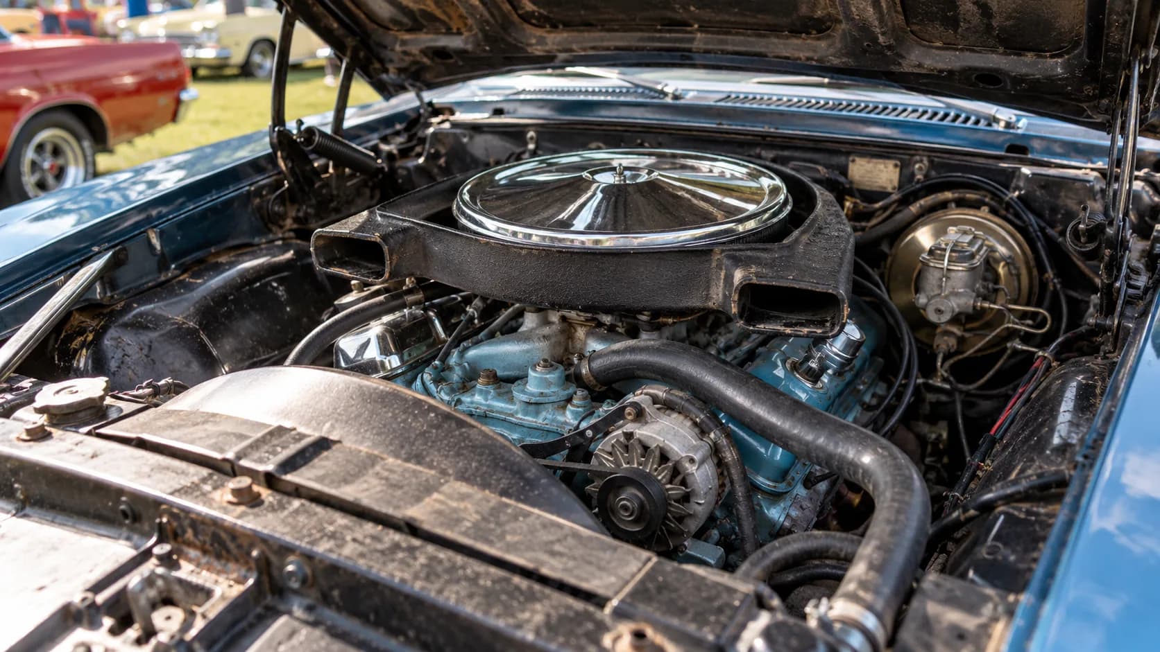 Hood up at a show field: a blue V8, a chrome lid and a pair of air intakes ready to breathe. Pontiac's Ram Air engines made the Judge, and the codes on the block still settle argum