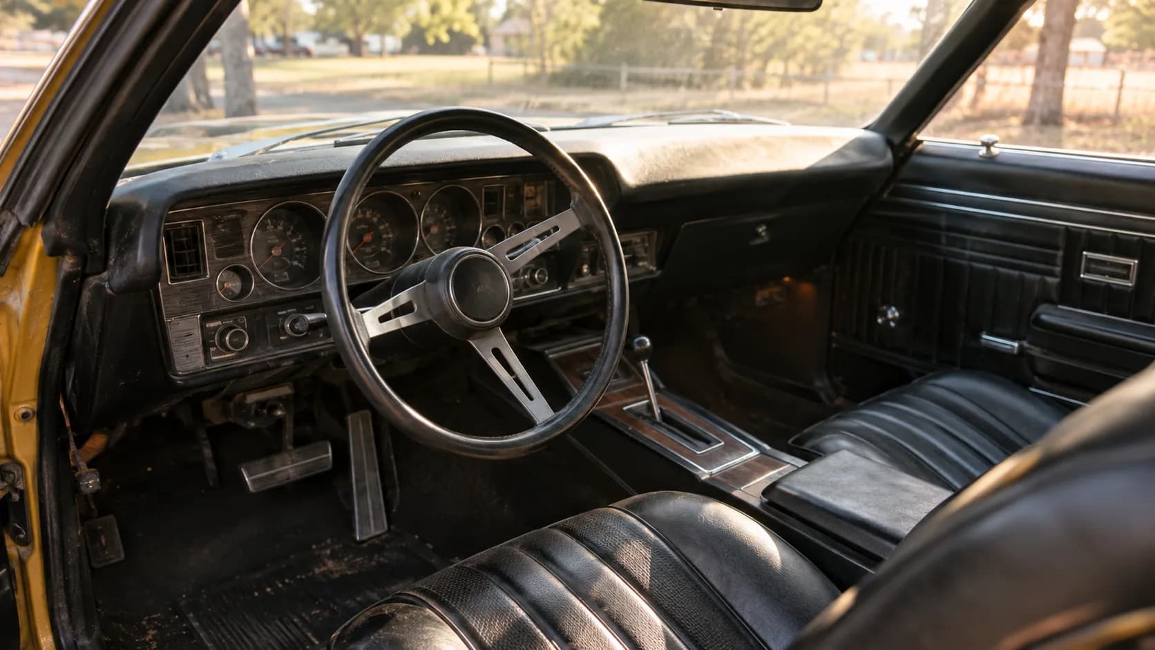 Interior of a 1970 Buick GSX: black bucket seats, console shifter and round gauges in afternoon light