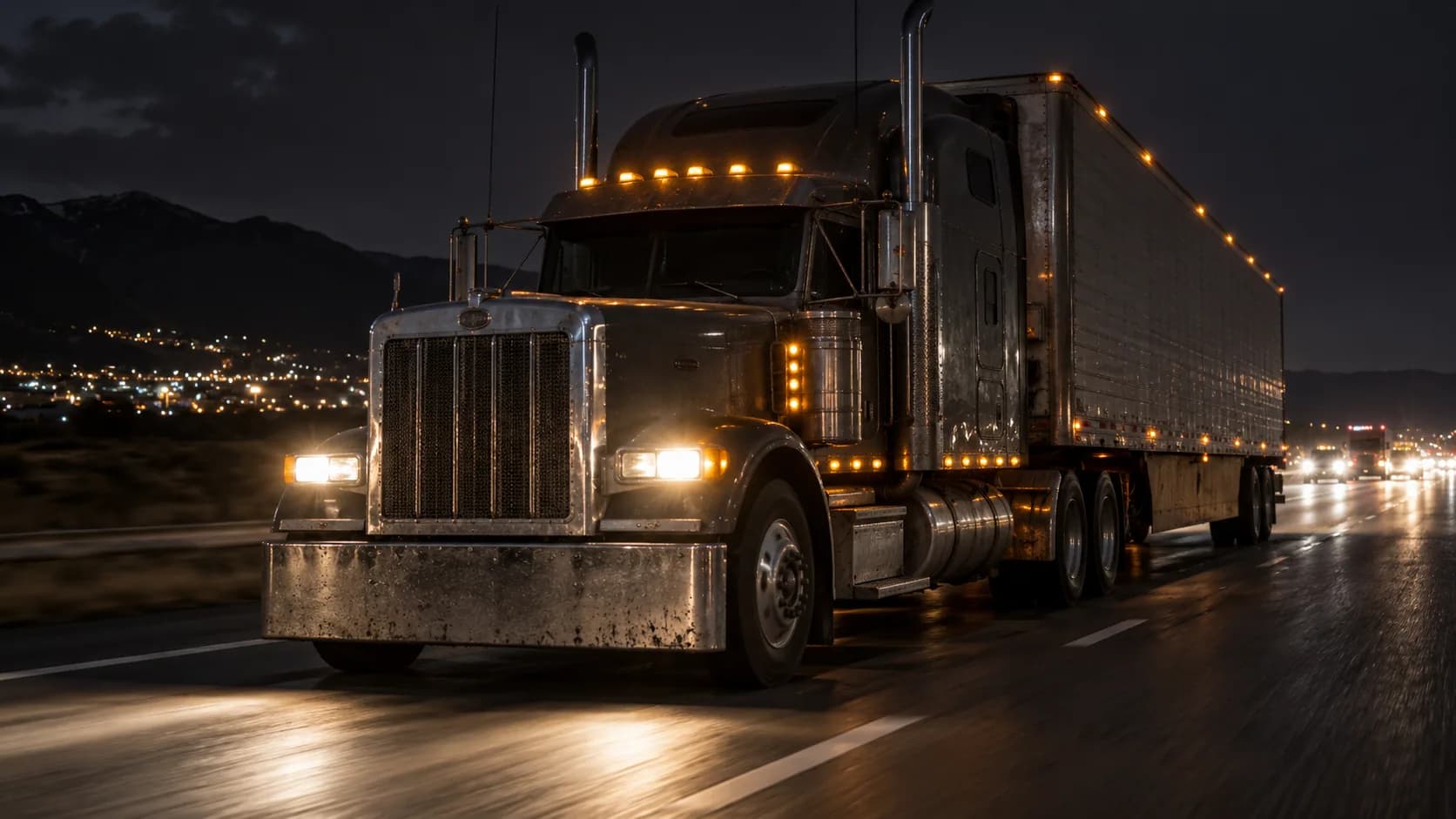 Marker lights glowing, stacks up, a long-hood running a wet highway at night with the city lights behind. Plenty of drivers swore by the flat hood while Peterbilt was chasing bette
